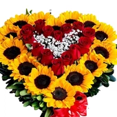 Arreglo foral en forma de corazón con girasoles y rosas en el centro.