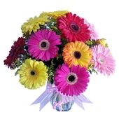 Hermoso florero transparente de 12 gerberas de colores y fino follaje, con moño.