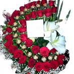 Arreglo floral en forma de media luna compuesto por rosas rojas, chocolates y casa-blanca